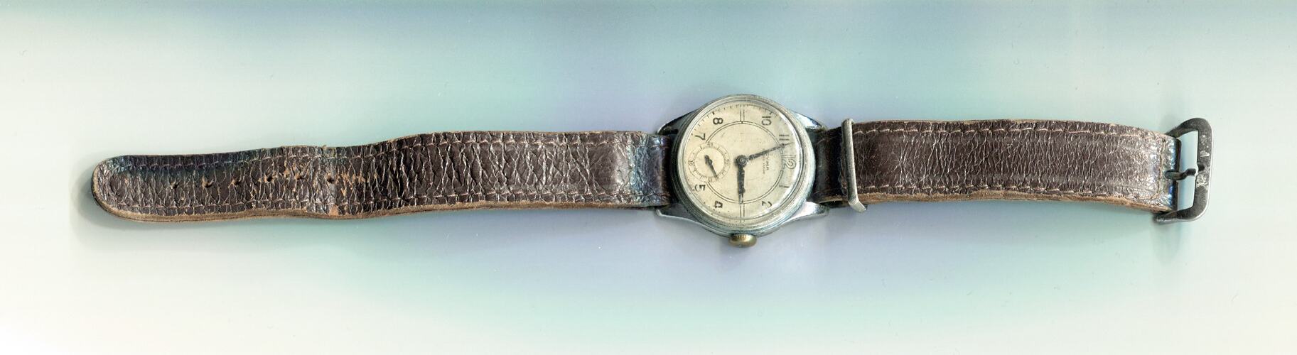Wrist watch with brown wornleather band and white face,
