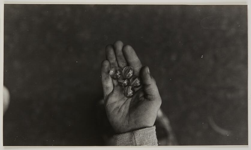 Five glass marbles displayed in the palm of a child's hand.