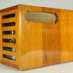 Control panel housed in wooden box. Open slats at one end.