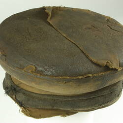 Three-quarter overhead view of old battered nightsoil collector's khaki flat top cap