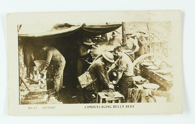 Soldiers in a makeshift kitchen using a machine to mince meat.