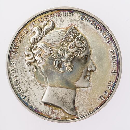 Silver medal with profile of woman facing right.