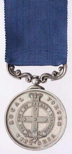 Round silver medal with ornate mount suspended from blue ribbon. Medal has crown, cross and text.
