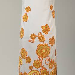 Back of long sleeveless white cotton dress with orange and yellow floral printed pattern.