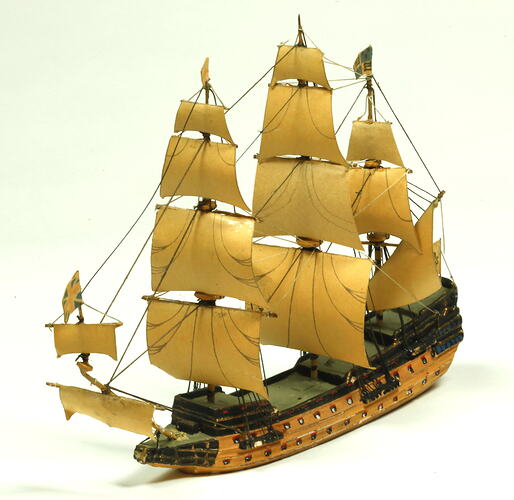 Three quarter view of three masted ship with wooden hull.