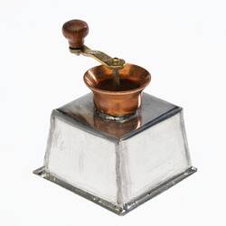 Miniature coffee grinder made from silver and copper. Brass handle on top.