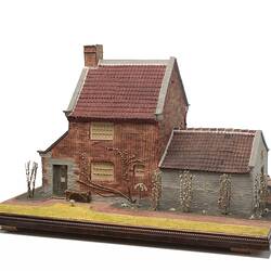 Model of red brick cottage and garden made from icing.