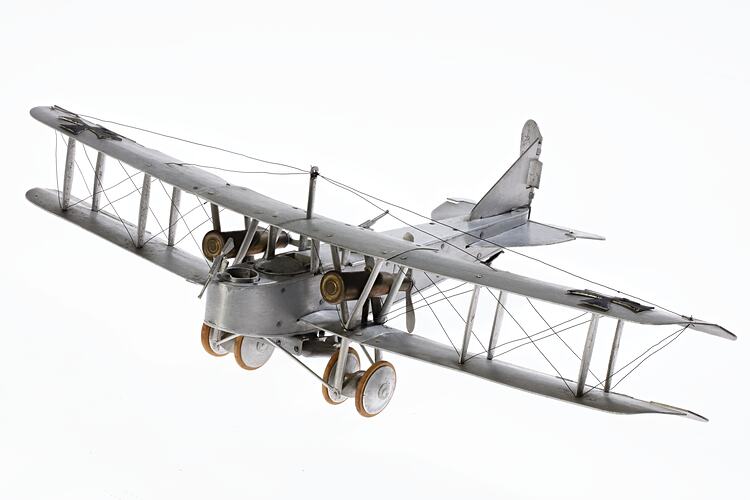 Model of a bi-plane made mostly of aluminium sheet metal. It has two pairs of wheels at front.