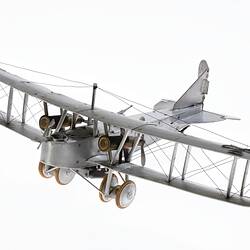 Model of a bi-plane made mostly of aluminium sheet metal. It has two pairs of wheels at front.