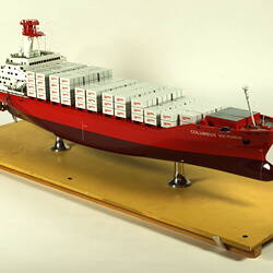 Container ship with red hull three quarter view.