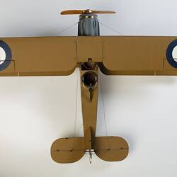 Model biplane aeroplane painted mustard. Top view. Each wing has a large roundel coloured blue, white and red.