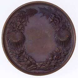Round medal with ornate floral framing. No engraved text.