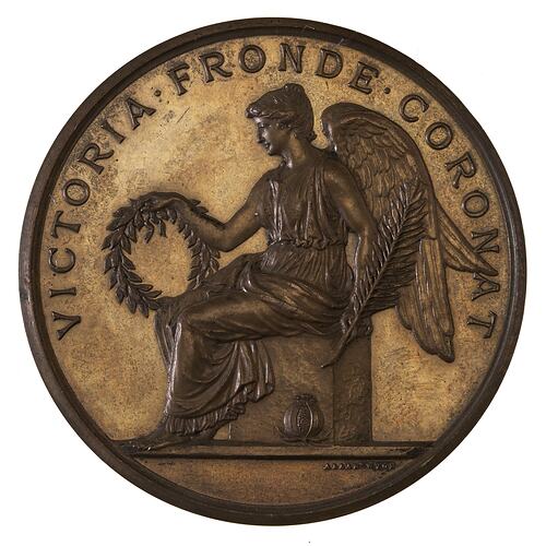 Round medal with seated winged Victory facing left holding a wreath and olive branch. Text around above.