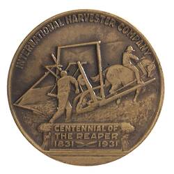 Round brown medal with horsedrawn reaper. Text around & below.