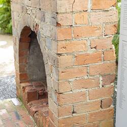 Red brick chimney with arched fireplace. Front and side of hearth from left side.
