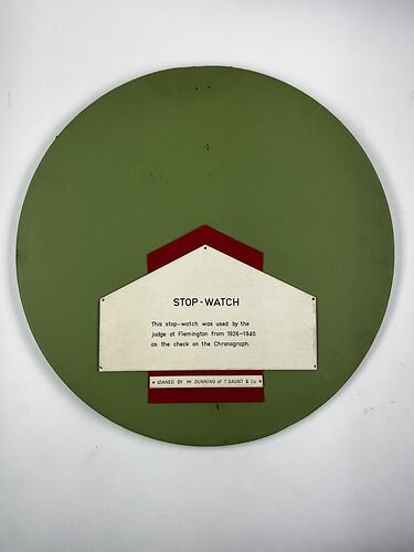 Round green exhibition panel with white label and black text.