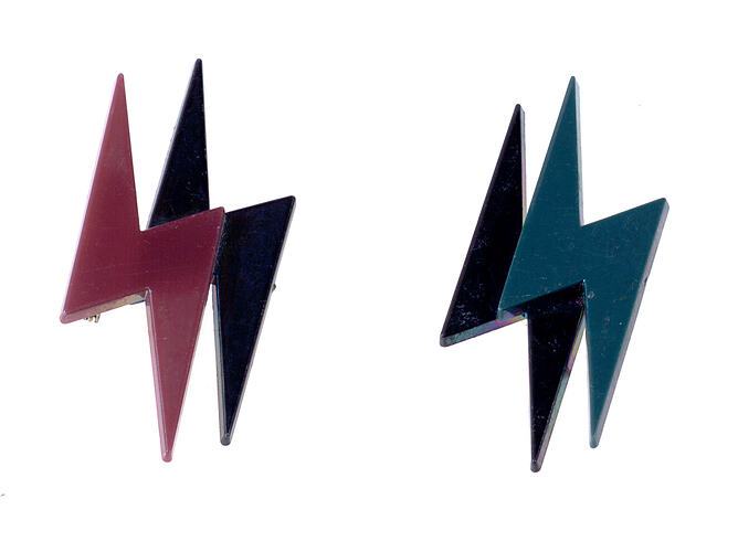 Two lightning bolt brooches in pink and blue.