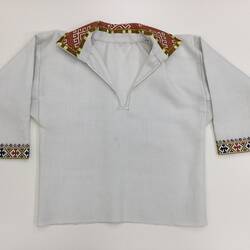 Cream shirt with long sleeves. Colourful embroidered edging at collar and cuffs.