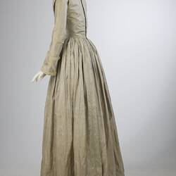 Pale grey striped silk dress with long sleeves and long skirt. Left profile.