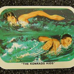 Card with two figures swimming in opposite directions in green blue water.