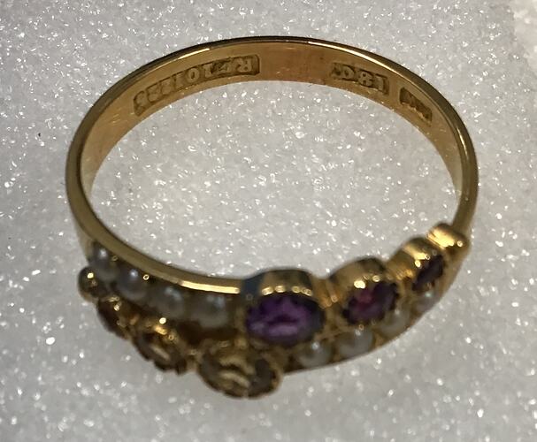 Gold ring featuring two parallel rows: one set with four evenly sized pearls and three graduated amethysts, the other alternating three graduated citrines with four evenly sized pearls.