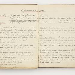 Open book with off white ruled pages. Handwritten text.