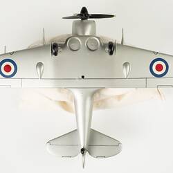 Underside of model aeroplane, silver with a black propeller and wheels.