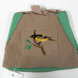 Tea cosy decorated with black and yellow bird.