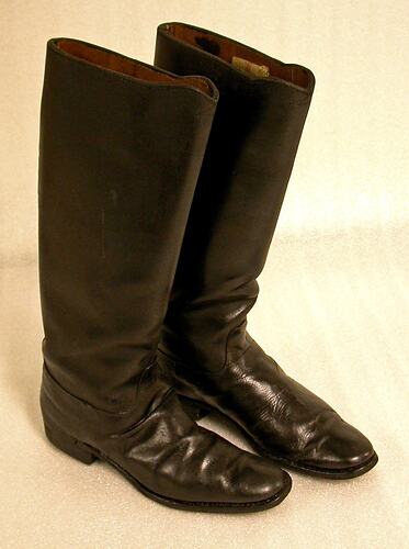Black leather knee-high boots, with low heels.