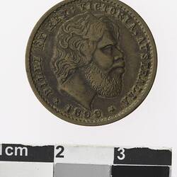 Round bronze coloured medal with profile of a bearded man in centre, text surrounding.