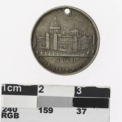 Round gold coloured medal with building and text below.