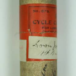 Wooden cylinder with red label.