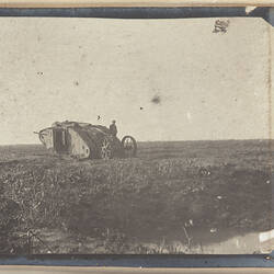 Tank in field with trailer and soldier standing on trailer.