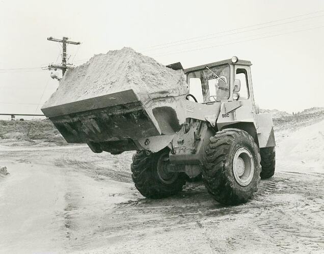 Man operating a front end articulated loader in a sand pit.