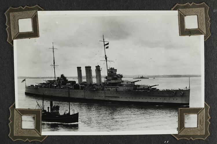 Military ship with smaller boat in foreground.