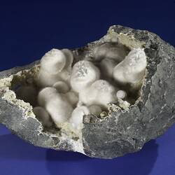 Broken round rock with small white crystals inside.