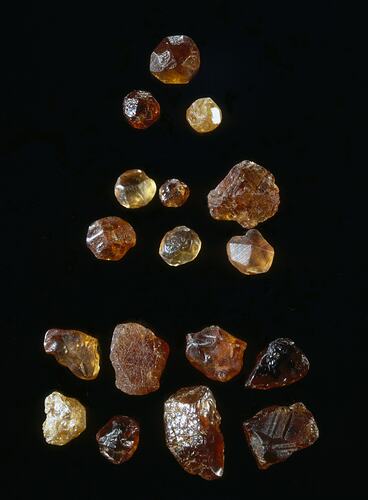 17 rouch, red and orange sapphires arranged in three groups.