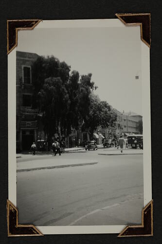 Street scene with cars, pedestrians and buildings in background.
