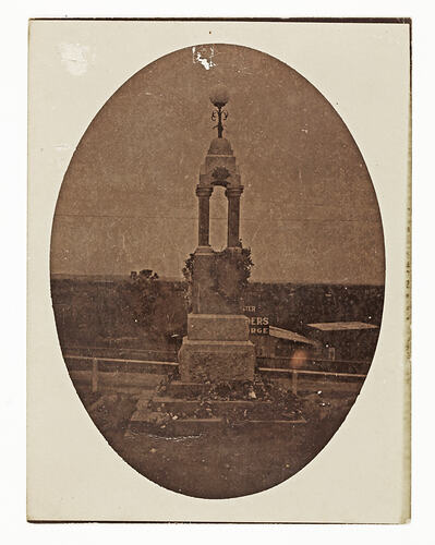 Black and white photograph in oval mount of World War I monument.