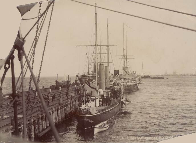 Several ships in a line moored at a wharf.
