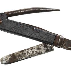 Metal folding knife with wood handle, warn and rusted, unfolded position.