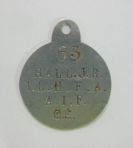 Silver disc with loop and stamped text.