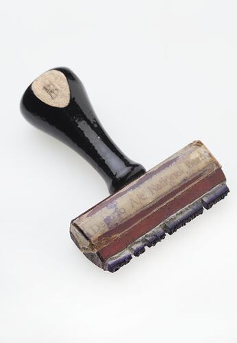 Red-brown wooden stamp with black handle.
