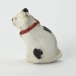 White cat figurine. Black spots and red collar. Left profile view.