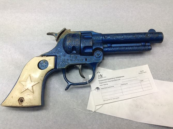 Blue metal toy revolver with cream handle.