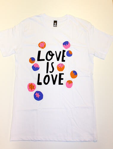 White t-shirt with printed pink, blue and orange circles. Central black text.