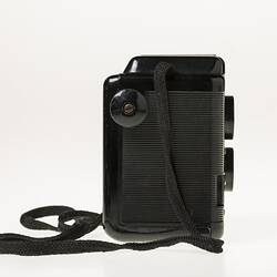 Box camera with black plastic body, black shoulder strap. Right profile.