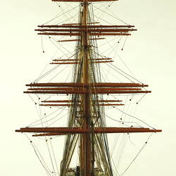 front view of three masted ship with red hull.