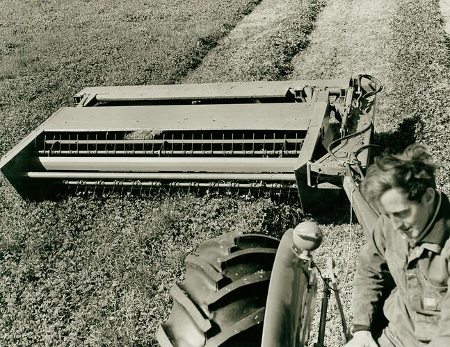 Man driving a tractor coupled to a windrower.
