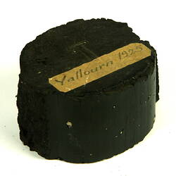 Black briquette with paper label.